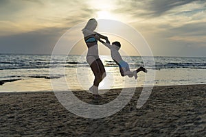 Young mother and smiling baby boy son playing on the beach on the Sunset. Positive human emotions, feelings, joy. Funny cute child