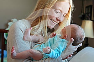 Young Mother Smiling at Newborn Baby in Home Nursery