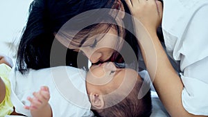 Young mother snuggle with her baby on the bed