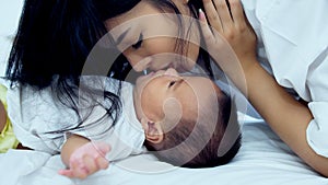 Young mother snuggle with her baby on the bed