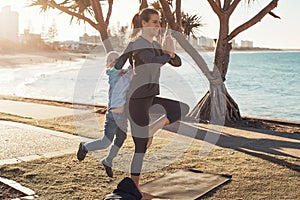 Young mother and son doing gymnastics and stretching in the city park on sunset