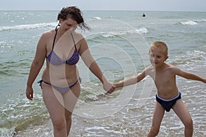 Young mother and son having fun on the beach