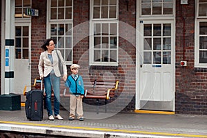 Young mother and son waiting for train on railway station