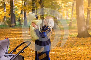 A young mother with a stroller is talking on her mobile phone while walking in the park