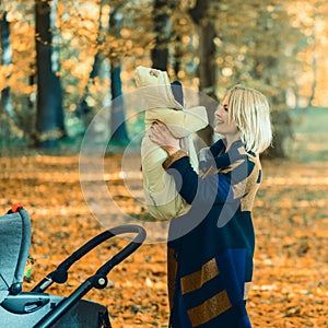 A young mother with a stroller is talking on her mobile phone while walking in the park