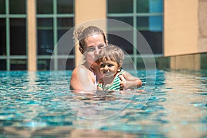 Young mother swimng with her little daughter in the pool on the roof of a skyscraper in a metropolis
