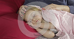 Young mother taking care of her little baby girl while she sleep. Girl on bed