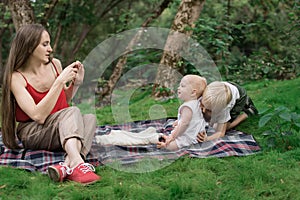 Young mother taking pictures of her children on phone. Picnic with the whole family