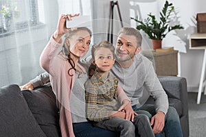 Young mother taking a selfie with her son and husban using smartphone while sitting