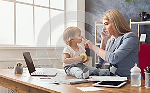 Young mother talking on phone and spending time with baby