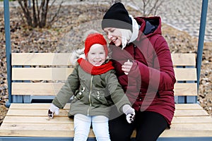 Young mother talking to her cute little daughter outdoors sitting together