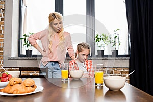 young mother talking with upset little daughter sitting at table