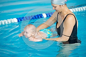 Young mother teach her little son, how to swim in a swimming poo