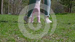 A young mother teaches her daughter how to walk. In the park on the green grass.