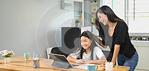 A young mother is teaching a daughter to do homework.