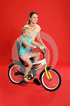 Young mother teaching daughter to ride bicycle