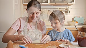 Young mother teaching her little son baking sweet roll with jam filling. Children cooking with parents, little chef