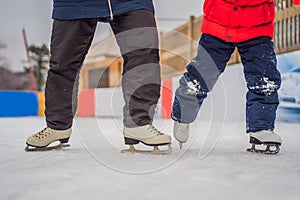 Young mother teaching her little son ice skating at outdoor skating rink. Family enjoy winter on ice-rink outdoors