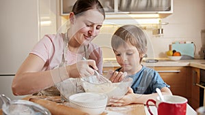 Young mother teaching her little son mixing dough for biscuit or cake. Children cooking with parents, little chef