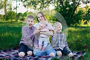 Young mother and three children having fun in nature. Happy playful family outdoors