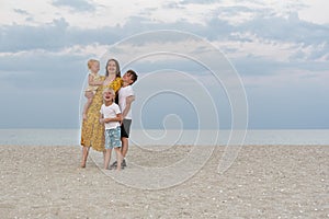 Young mother and three children having fun on summer vacation on the beach. Family on a sea