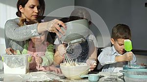 A young mother with three children prepares dough for dumplings and ravioli. Slavic cuisine, Russian dishes