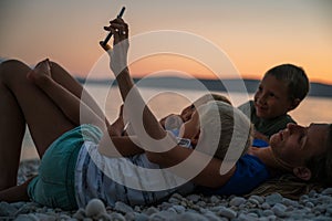 Young mother with three kids lying on pebble beach