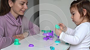 Young mother with toddler child playing play dough at home. Home activity with toddler. Bonding family time