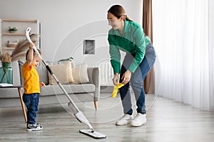 Young mother and toddler son cleaning at home together, mom teaching kid chore help home work