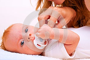 Young mother trying to give baby`s dummy