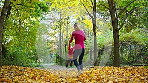 Young mother turns his son around, Happy mother holding his little child`s arms and spinning him in circles on a autumn day