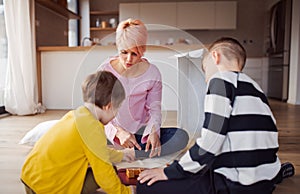Young mother with two children playing board games on the floor.