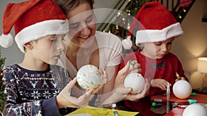 Young mother with two kids preparing for Christmas and making handmade decorations. Winter holidays, family time