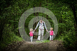 Young mother walk with identical twins in woods, young pretty girls with blond curly hair, freedom, joy, movement, outdoor
