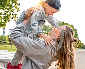 Young mother woman happy plays with little boy 3-5 years old, in city park, autumn clothes on nature, fun joy and