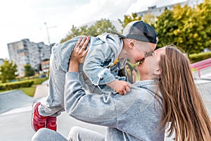 Young mother woman happy plays with little years old boy in city park, autumn clothes on nature, fun joy and emotions of