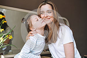 Young mother woman with long hair with little tween girl daughter in pajamas having fun in the morning at home