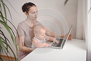 Young mother work studying from home with laptop computer during quarantine, little cute toddler baby on lap. Home office,