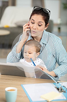 young mother working home with baby sling