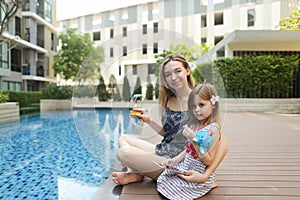 Young mother working on vacations with laptop near swimming pool