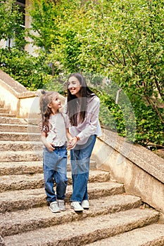 A young mother with a young daughter comes down the stairs. A woman holds a girl`s hand and talks to her