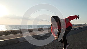 Young motivated girl is preparing to run on promenade at sunsetin nature. photo