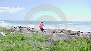 Young motivated sportive woman running on a trail towards the camera. Strong stormy sea on the background