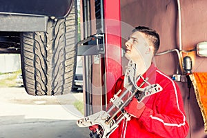 Young motor mechanic holding a piece of equipment in an automotive workshop