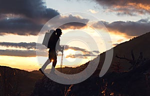 Young mountaineer standing with backpack on top of a mountain