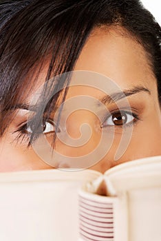 Young mulato woman hiding herself behind a book photo