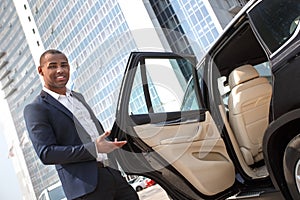 Young man manager standing with car door opened looking camera welcoming