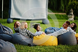 Young multi ethnic group of people watching movie at poof in open air cinema