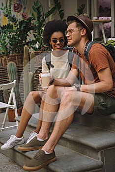 young multicultural couple with coffee sitting