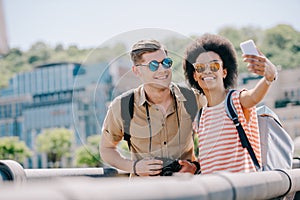 young multicultural couple of travelers taking selfie